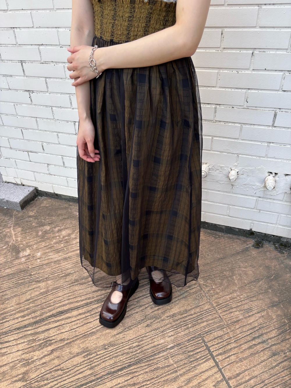 グリーン系のスカート、ホワイト系のTシャツ/カットソー、ブラウン系のスニーカーを着用したレディースの夏コーディネートの3枚目の写真