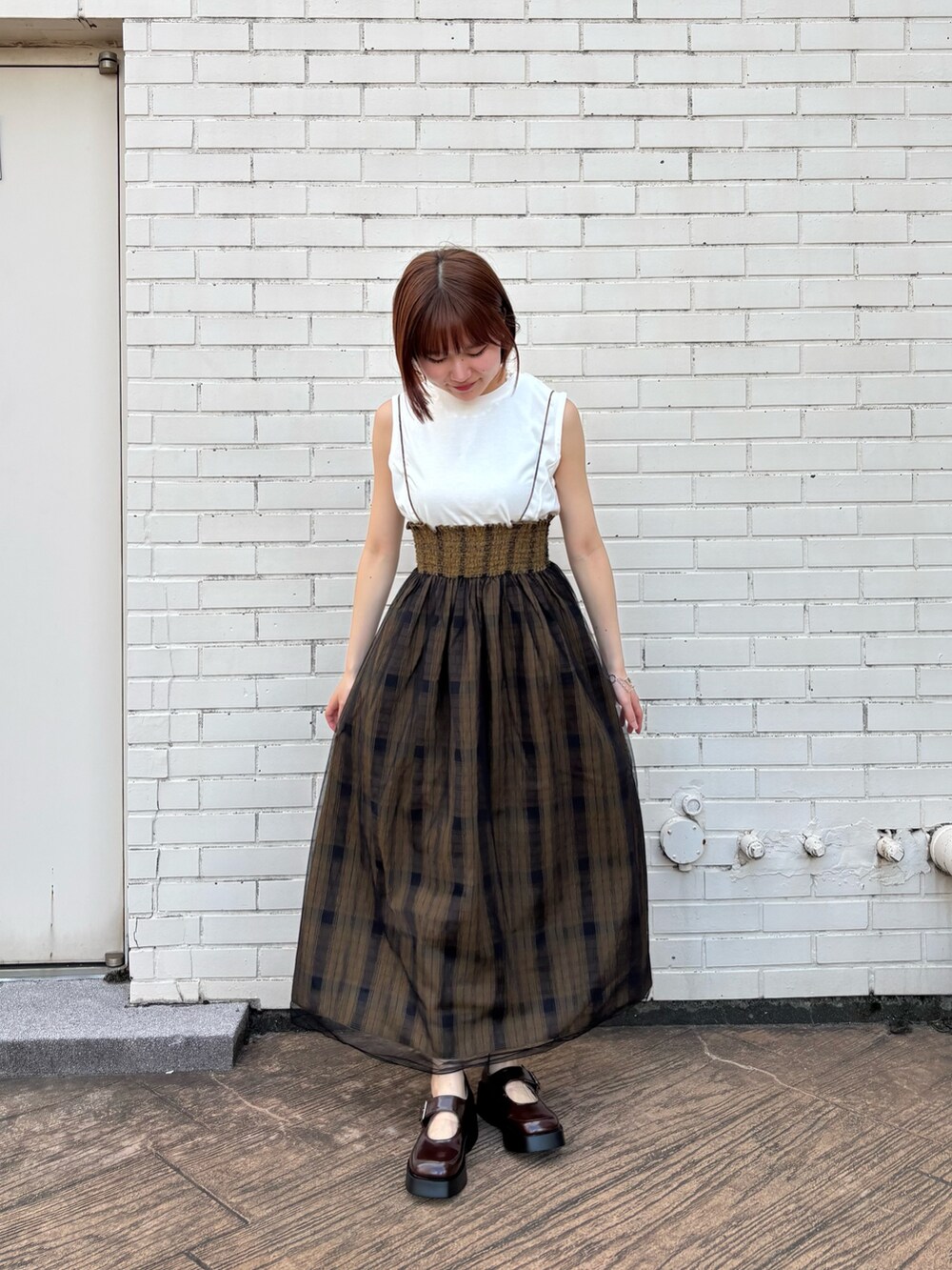 グリーン系のスカート、ホワイト系のTシャツ/カットソー、ブラウン系のスニーカーを着用したレディースの夏コーディネートの4枚目の写真
