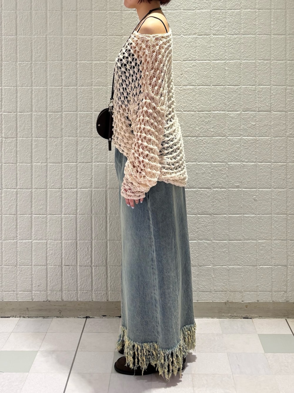 ホワイト系のニット/セーター、ブラウン系のショルダーバッグ、ブラック系のスカートを着用したレディースの春コーディネートの2枚目の写真