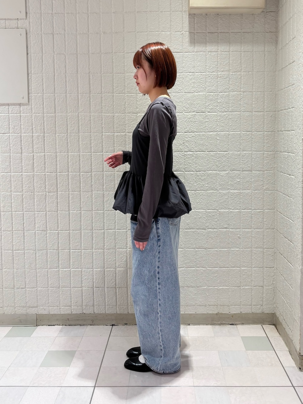 グレー系のTシャツ/カットソー、ブルー系のデニムパンツ、ブラック系のボストンバッグを着用したレディースの冬コーディネートの3枚目の写真