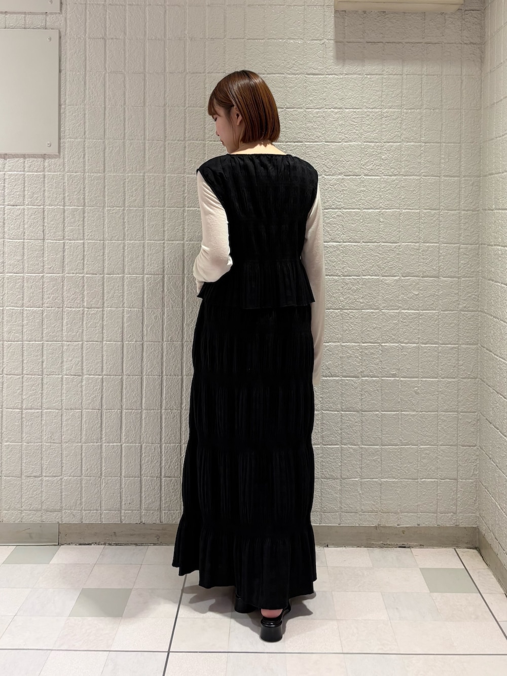 ブラック系のセットアップ、ホワイト系のTシャツ/カットソー、ブラック系のパンプスを着用したレディースの春コーディネートの3枚目の写真