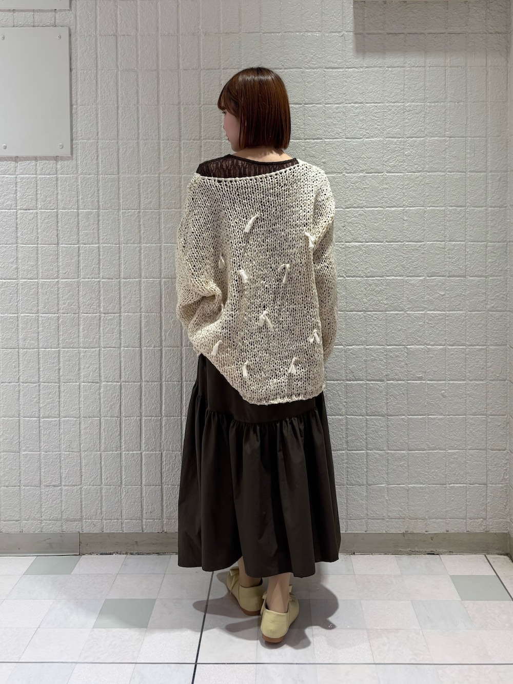 ブラウン系のTシャツ/カットソー、ホワイト系のニット/セーター、グリーン系のスカートを着用したレディースの冬コーディネートの3枚目の写真