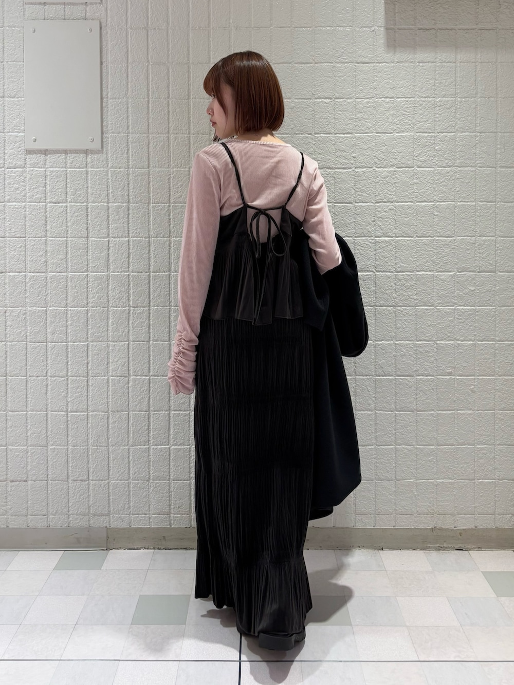 ピンク系のTシャツ/カットソー、ブラック系のステンカラーコート、ブラウン系のワンピースを着用したレディースの冬コーディネートの5枚目の写真