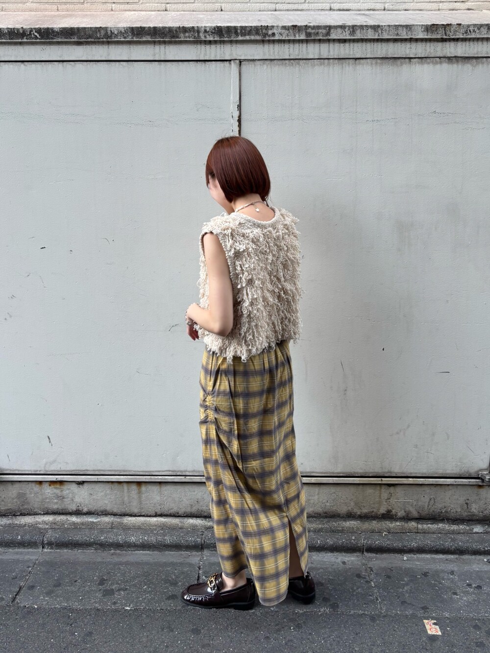 ベージュ系のベスト、イエロー系のスカート、ブラウン系のローファーを着用したレディースの夏コーディネートの2枚目の写真