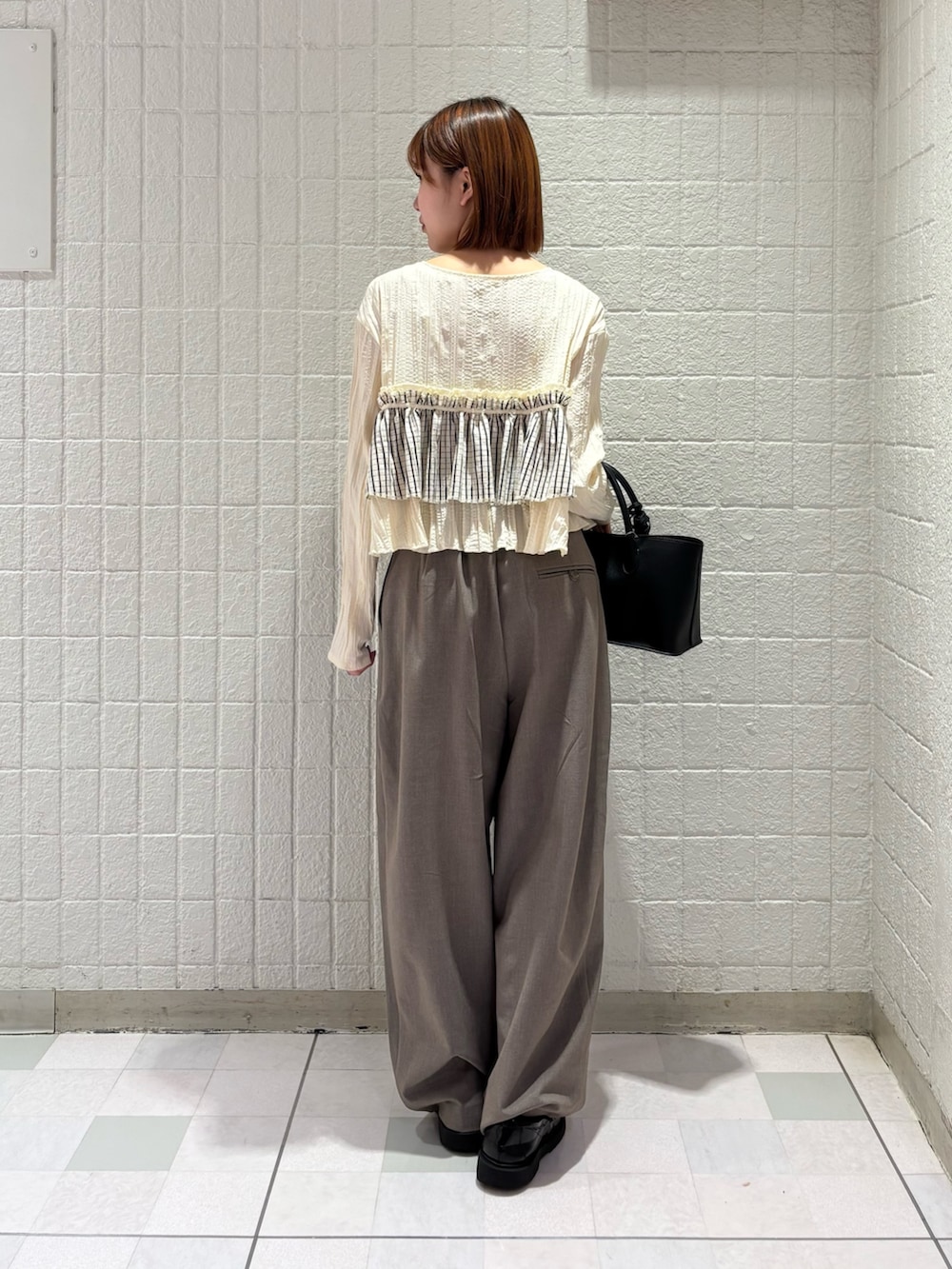 ホワイト系のシャツ/ブラウス、グレー系のその他パンツ、ブラック系のハンドバッグを着用したレディースの春コーディネートの3枚目の写真