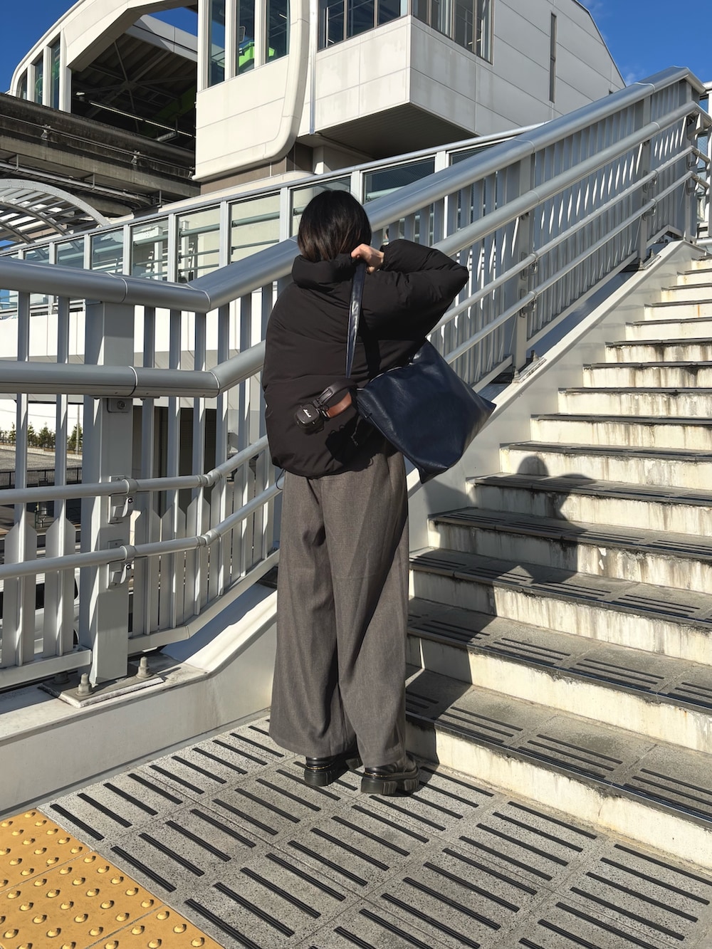 ブラック系のダウンジャケット/コート、ブラック系のTシャツ/カットソー、グレー系のスラックスを着用したレディースの冬コーディネートの2枚目の写真