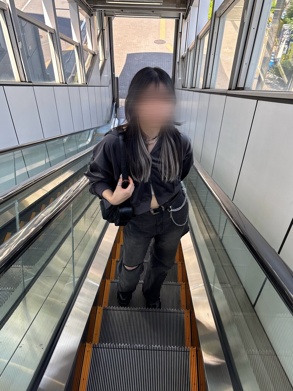 グレー系のパーカー、ブラック系のデニムパンツ、ブラック系のショルダーバッグを着用したレディースの秋コーディネートの2枚目の写真