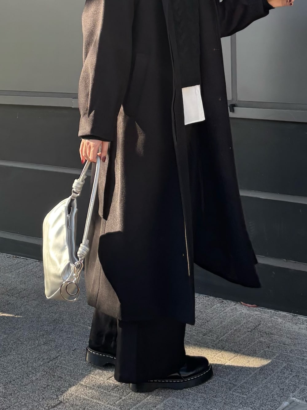 ブラック系のステンカラーコート、ホワイト系のシャツ/ブラウス、ブラック系のニット/セーターを着用したレディースの冬コーディネートの3枚目の写真