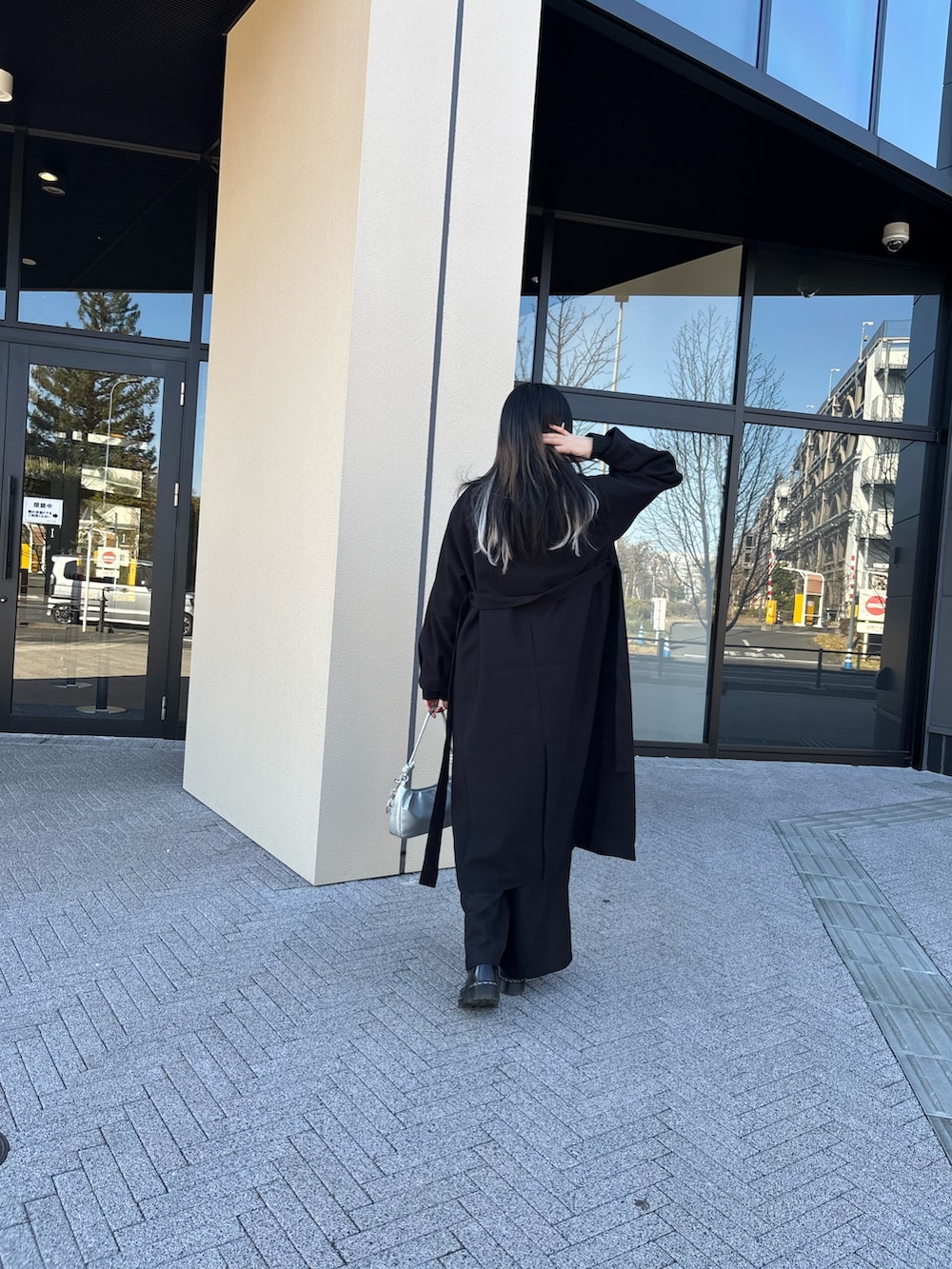 ブラック系のステンカラーコート、ホワイト系のシャツ/ブラウス、ブラック系のニット/セーターを着用したレディースの冬コーディネートの4枚目の写真