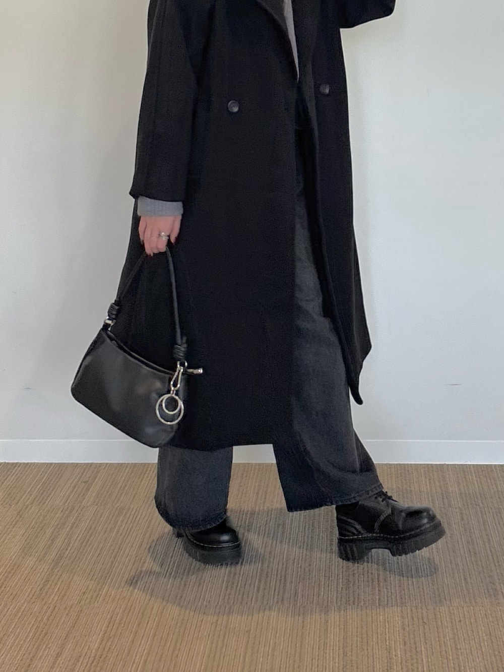 ブラック系のチェスターコート、ホワイト系のTシャツ/カットソー、グレー系のニット/セーターを着用したレディースの冬コーディネートの2枚目の写真