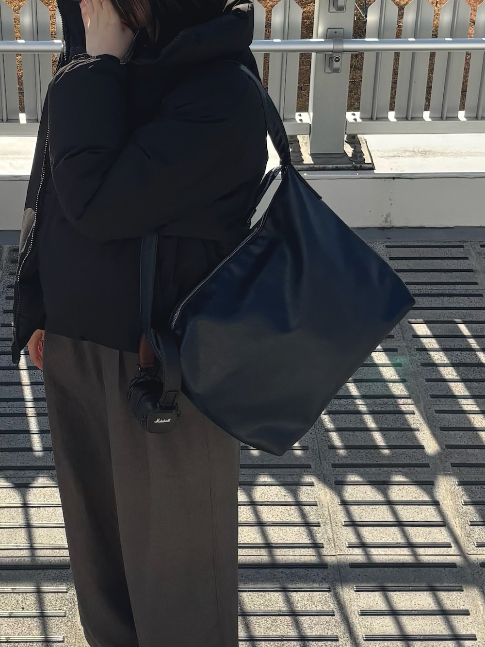 ブラック系のダウンジャケット/コート、ブラック系のTシャツ/カットソー、グレー系のスラックスを着用したレディースの冬コーディネートの3枚目の写真