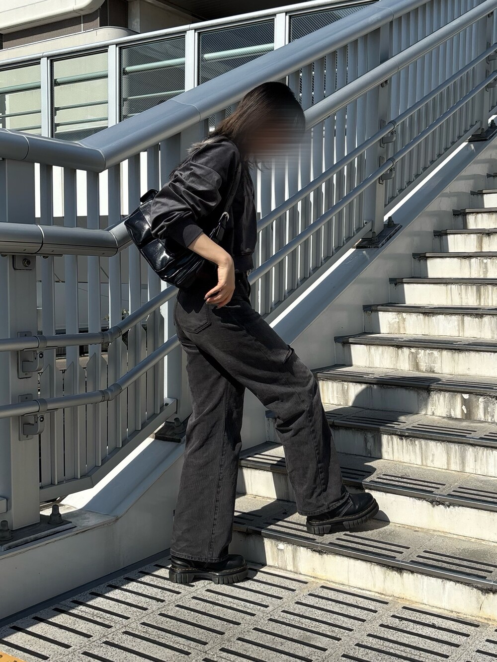 グレー系のパーカー、ブラック系のデニムパンツ、ブラック系のショルダーバッグを着用したレディースの秋コーディネートの4枚目の写真