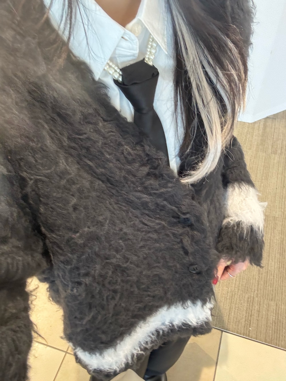 ブラック系のカーディガン/ボレロ、ホワイト系のシャツ/ブラウス、ブラック系のスラックスを着用したレディースの冬コーディネートの2枚目の写真