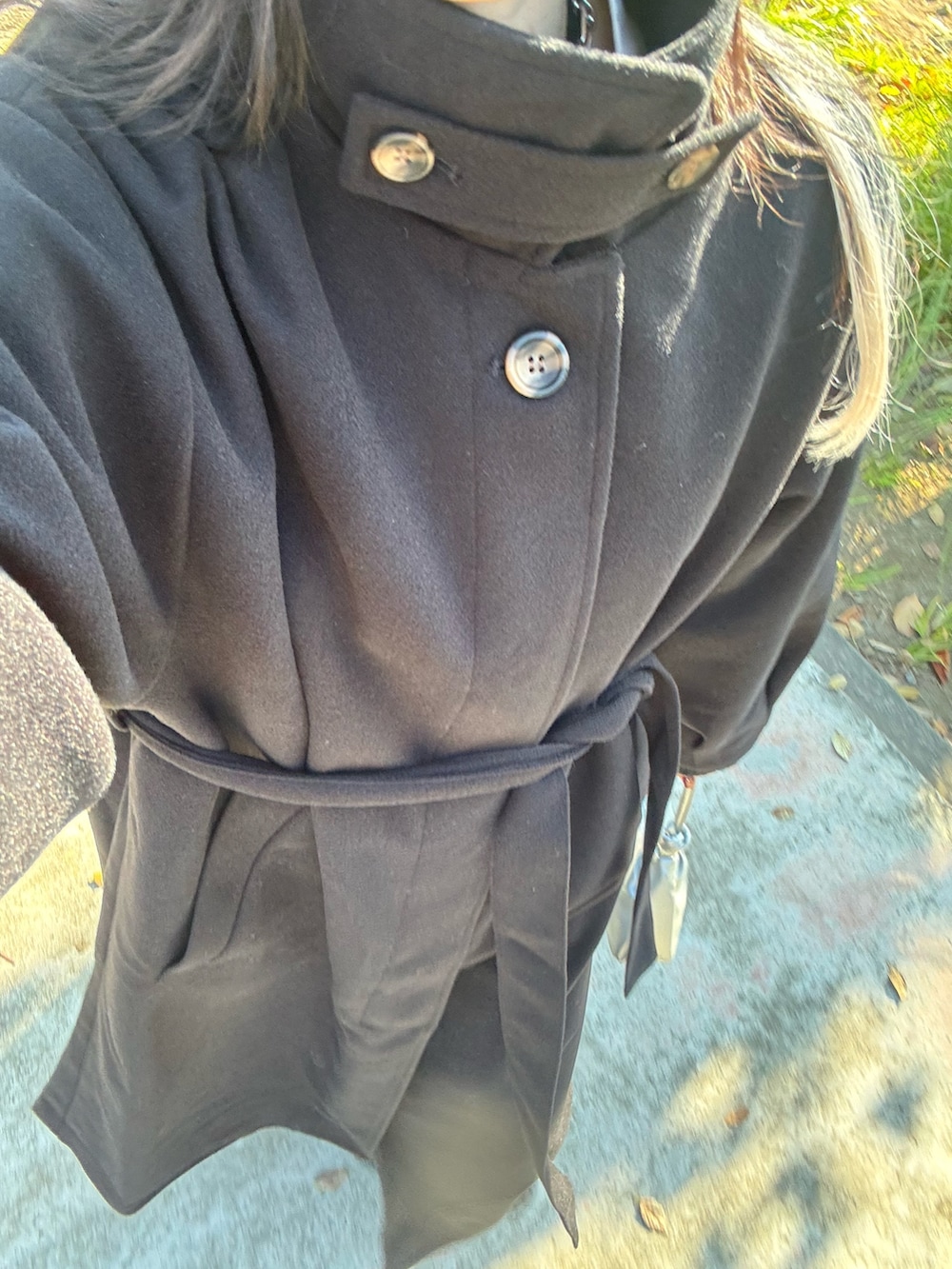 ブラック系のステンカラーコート、ホワイト系のシャツ/ブラウス、ブラック系のニット/セーターを着用したレディースの冬コーディネートの5枚目の写真