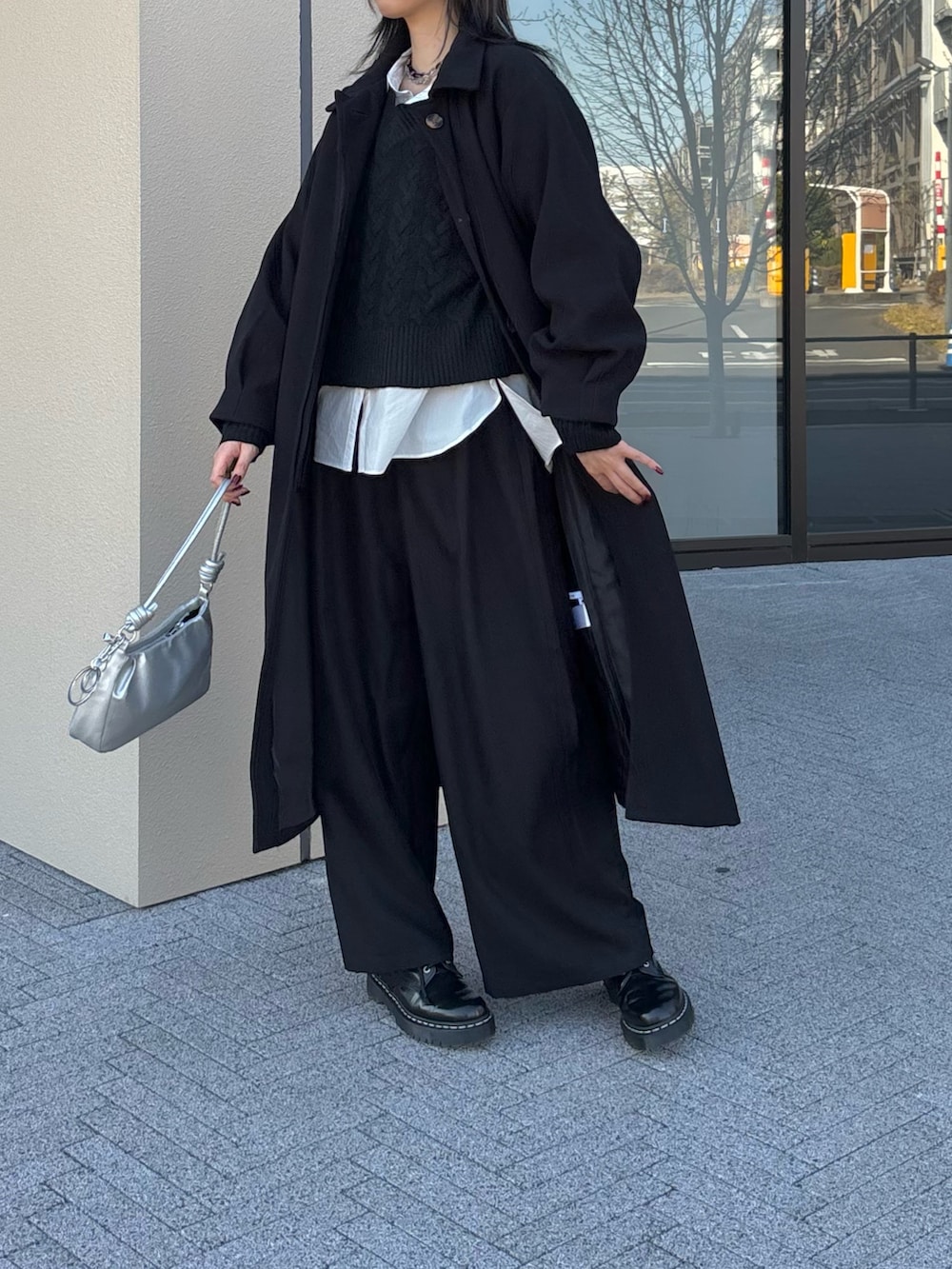 ブラック系のステンカラーコート、ホワイト系のシャツ/ブラウス、ブラック系のニット/セーターを着用したレディースの冬コーディネートの2枚目の写真