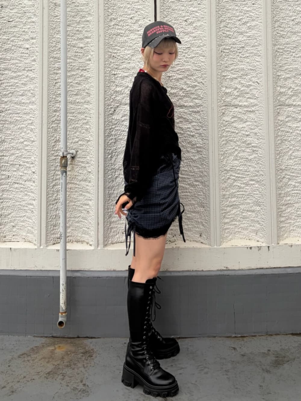 ブラック系のブーツ、ブラック系のニット/セーター、レッド系のキャミソールを着用したレディースの春コーディネートの3枚目の写真