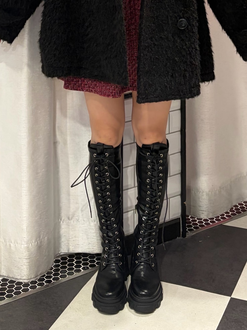 ブラック系のステンカラーコート、ブラック系のTシャツ/カットソー、レッド系のワンピースを着用したレディースの冬コーディネートの5枚目の写真