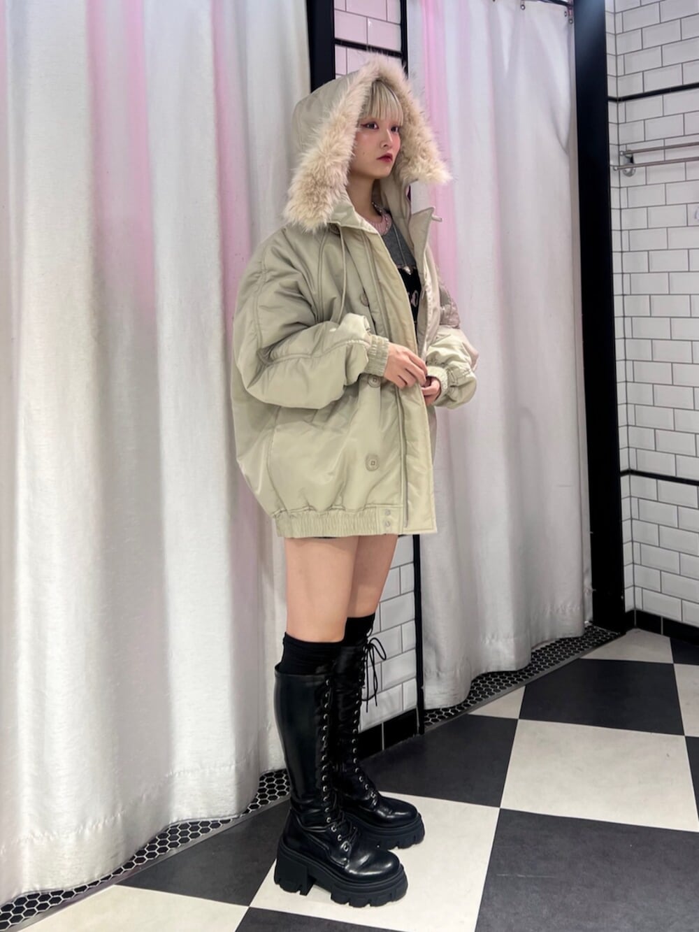 ブラック系のブーツ、ホワイト系のブルゾン、グレー系のニット/セーターを着用したレディースの秋コーディネートの2枚目の写真