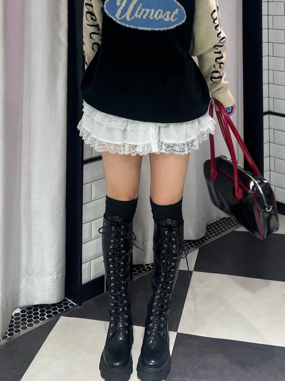 ブラック系のボストンバッグ、ブラック系のブーツ、ブラック系のニット/セーターを着用したレディースの秋コーディネートの4枚目の写真