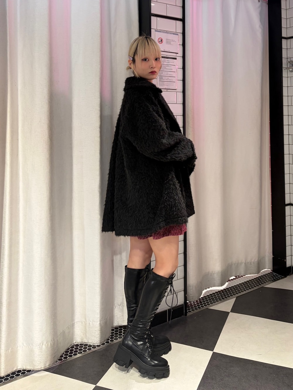 ブラック系のステンカラーコート、ブラック系のTシャツ/カットソー、レッド系のワンピースを着用したレディースの冬コーディネートの2枚目の写真