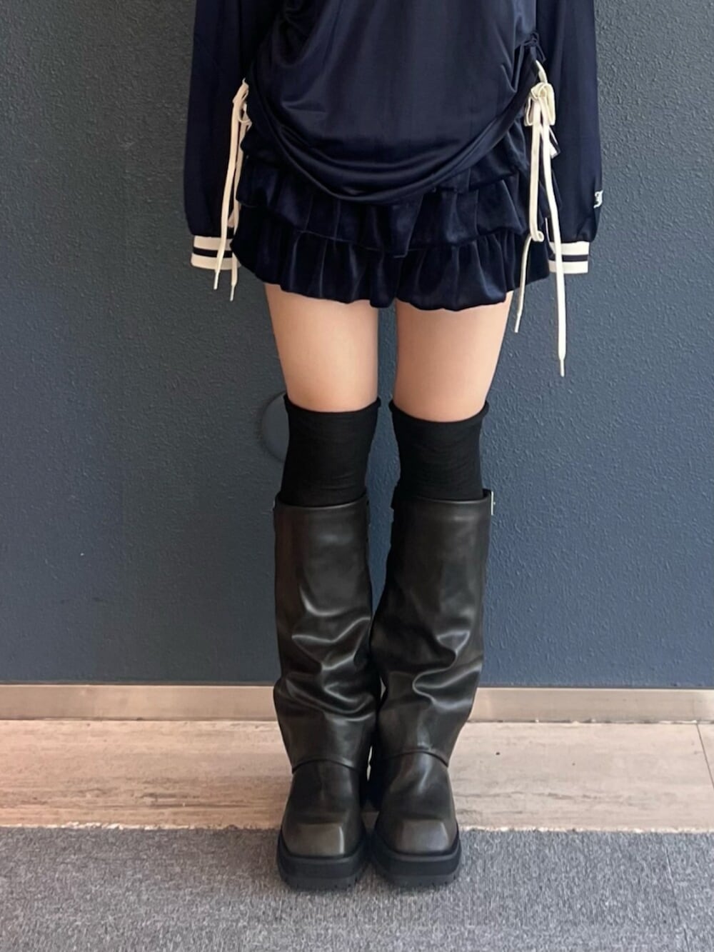 ブルー系のスカート、ブラック系のブーツ、ブルー系のTシャツ/カットソーを着用したレディースの秋コーディネートの5枚目の写真