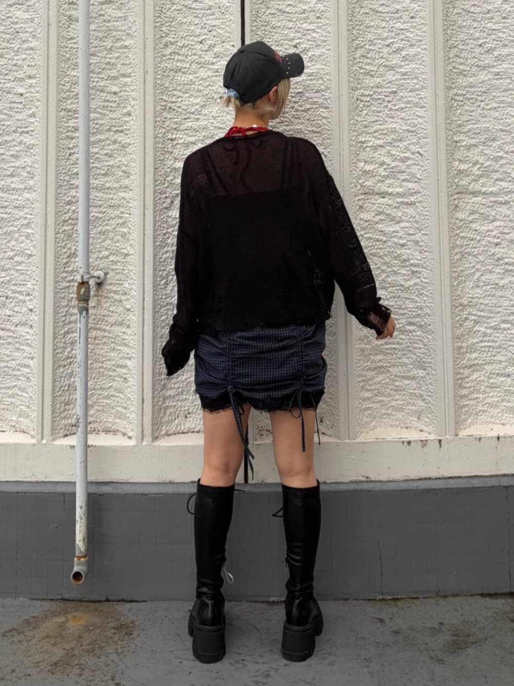 ブラック系のブーツ、ブラック系のニット/セーター、レッド系のキャミソールを着用したレディースの春コーディネートの4枚目の写真