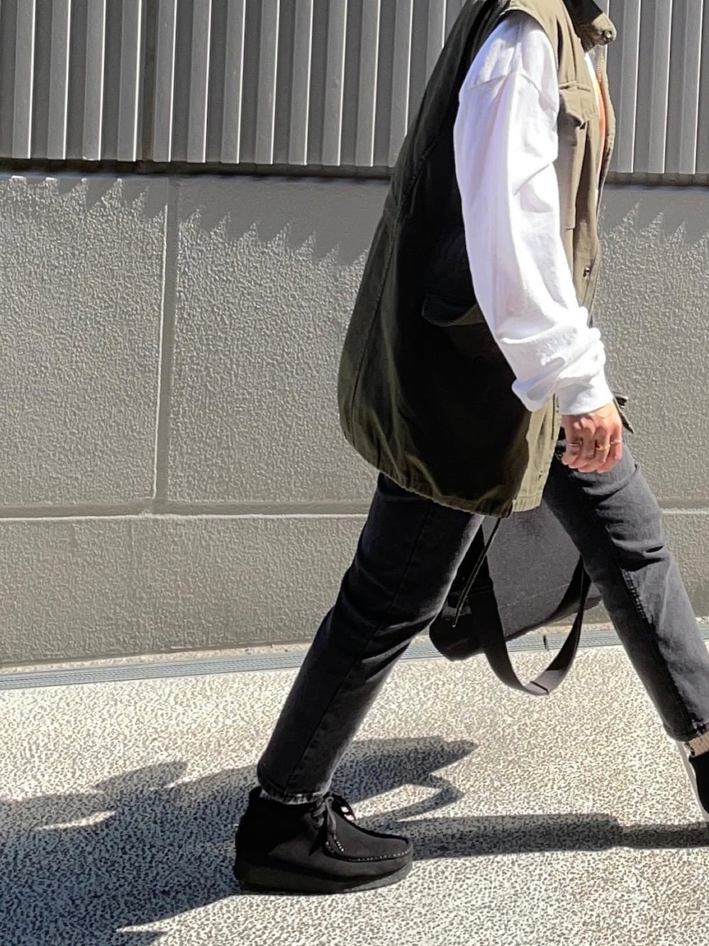 ブラック系のブーツ、グリーン系のベスト、パープル系のキャップを着用したレディースの秋コーディネートの2枚目の写真