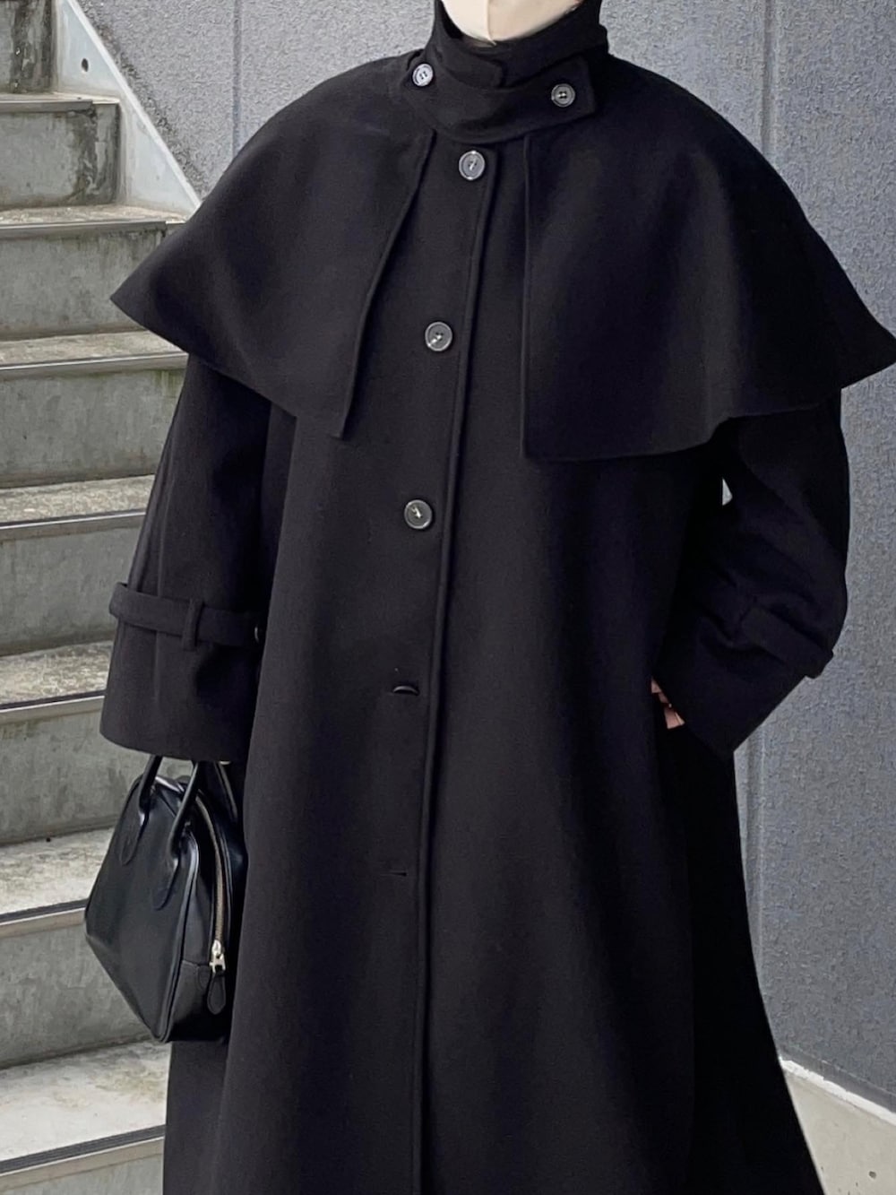 ブラック系のステンカラーコートを着用したレディースの秋コーディネートの3枚目の写真