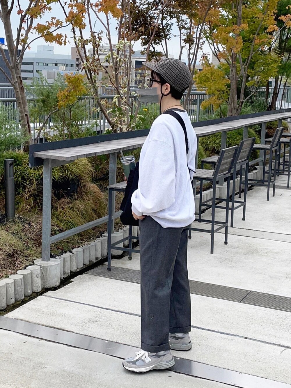 グレー系のスラックス、グレー系のスニーカー、ホワイト系のスウェットを着用したレディースの秋コーディネートの2枚目の写真