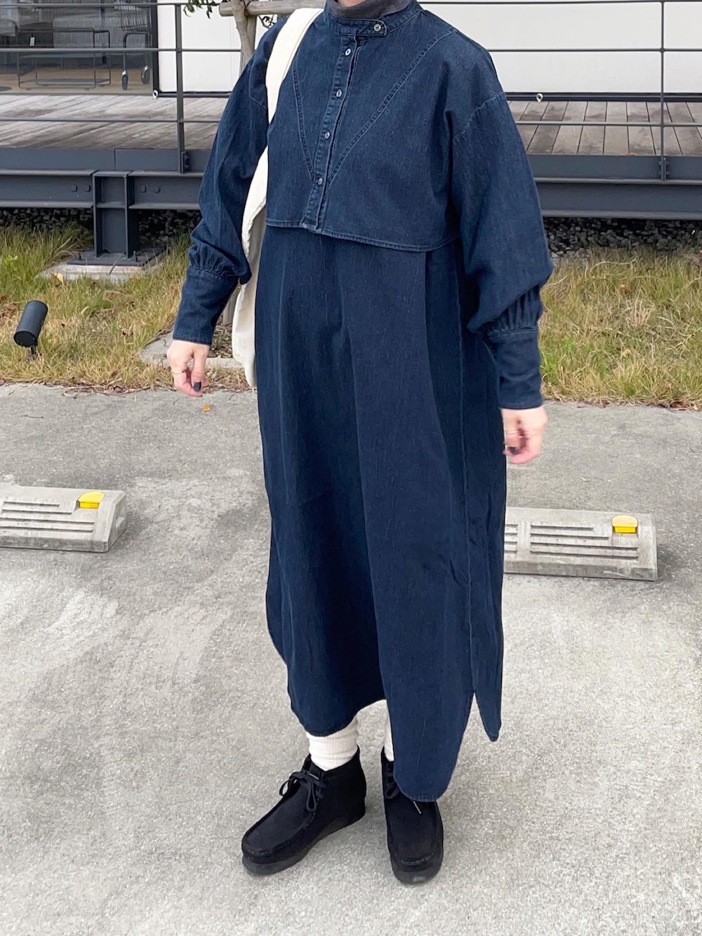 ブルー系のワンピース、ブラック系のブーツ、ホワイト系のトートバッグを着用したレディースの冬コーディネートの2枚目の写真