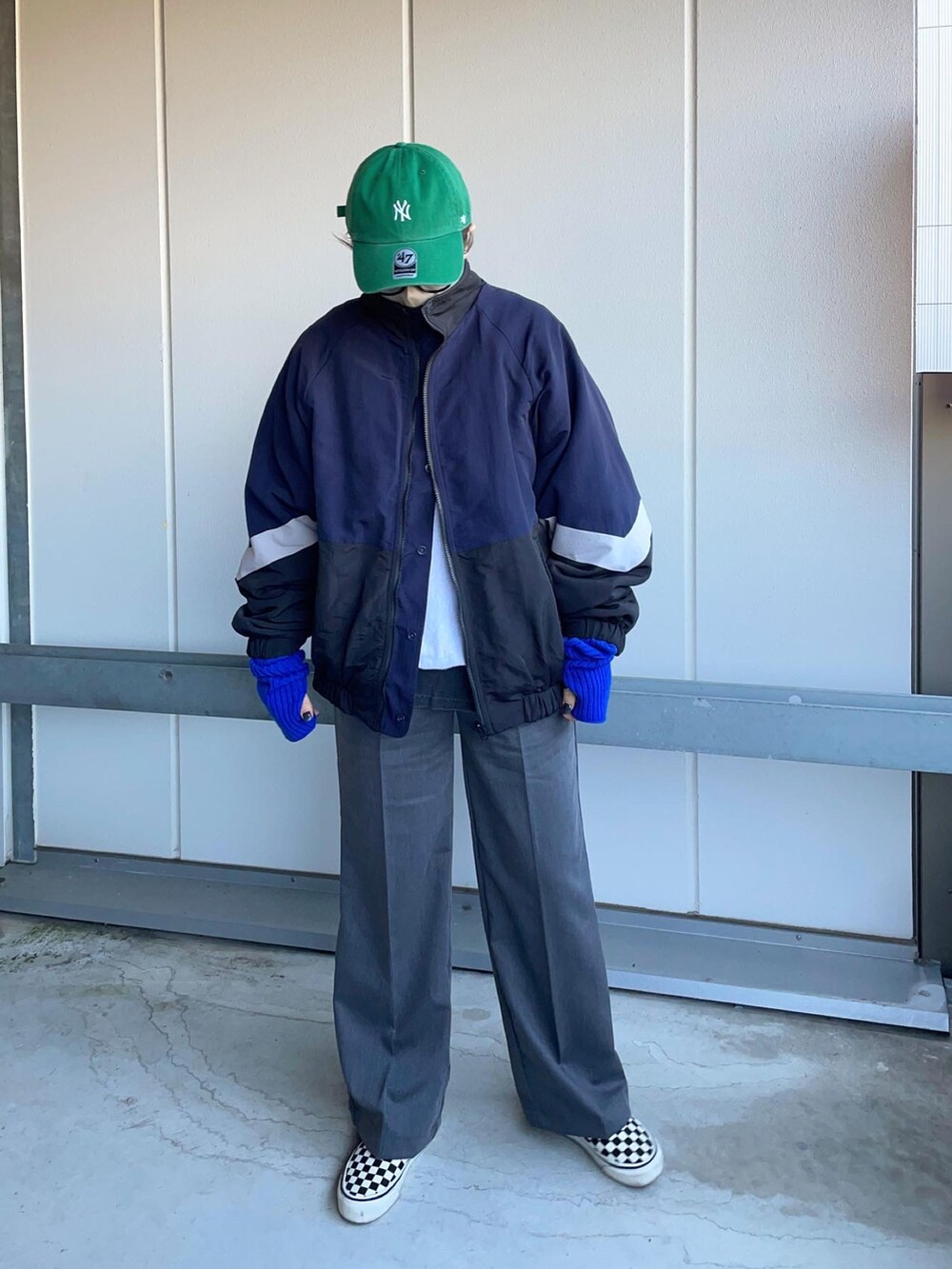 グレー系のスラックス、ブルー系のブルゾン、ホワイト系のスニーカーを着用したレディースの冬コーディネートの2枚目の写真