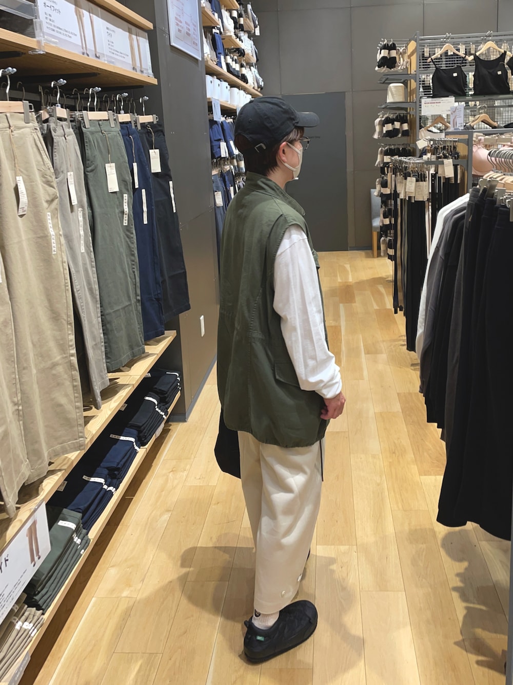 グリーン系のベスト、ベージュ系のその他パンツ、ブラック系のスニーカーを着用したレディースの秋コーディネートの2枚目の写真