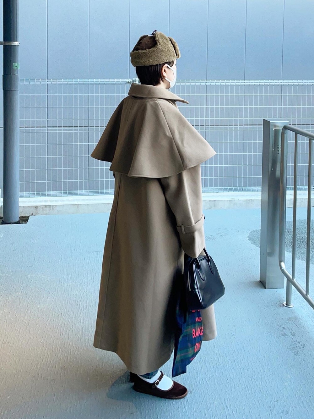 グリーン系のステンカラーコートを着用したレディースの冬コーディネートの4枚目の写真