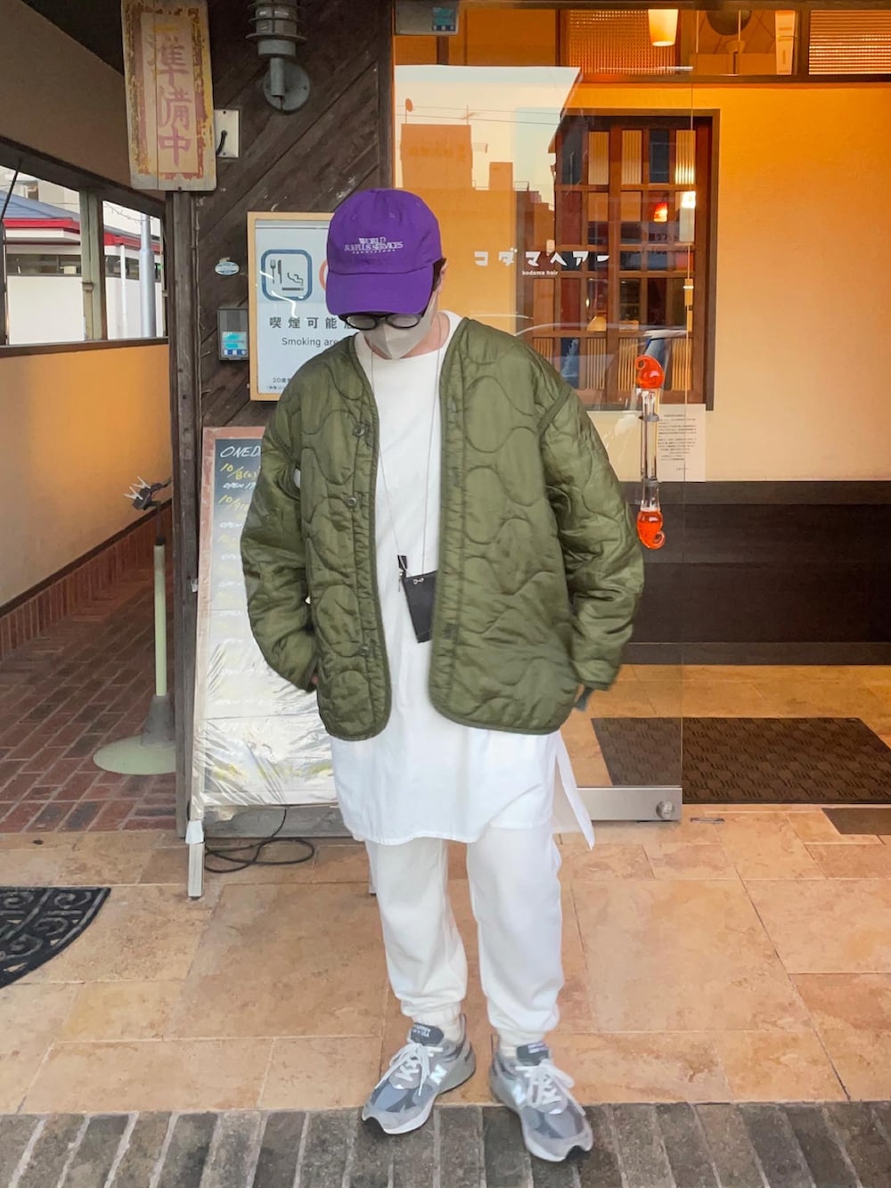 グレー系のスニーカー、グリーン系のノーカラージャケット、パープル系のキャップを着用したレディースの秋コーディネートの2枚目の写真