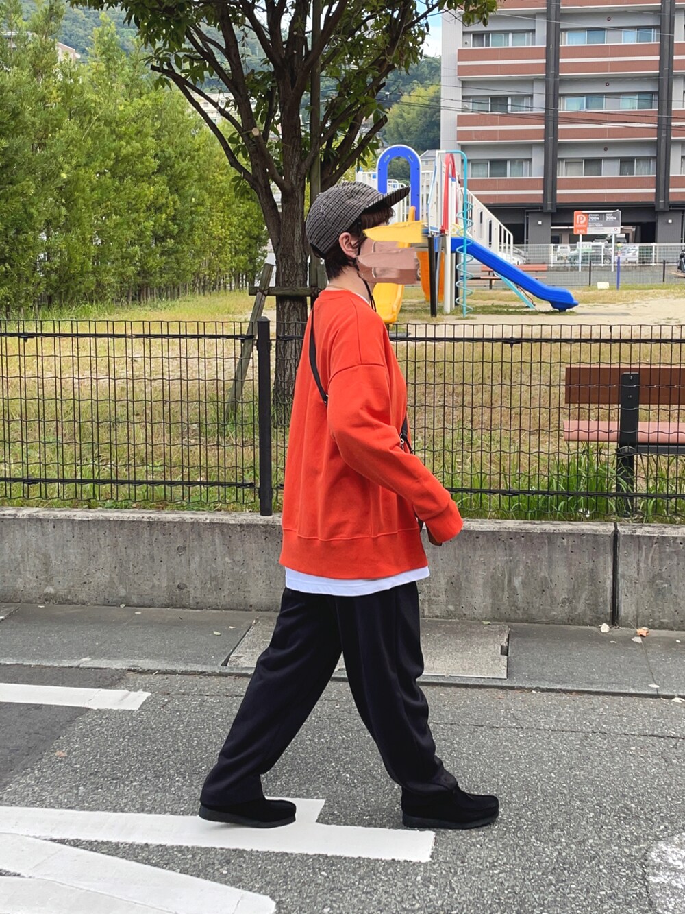 オレンジ系のスウェット、ブラック系のスウェットパンツ、ブラック系のブーツを着用したレディースの秋コーディネートの2枚目の写真