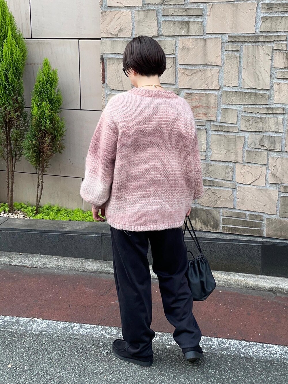 ブラック系のスウェットパンツ、ブラック系のブーツ、ピンク系のニット/セーターを着用したレディースの秋コーディネートの2枚目の写真