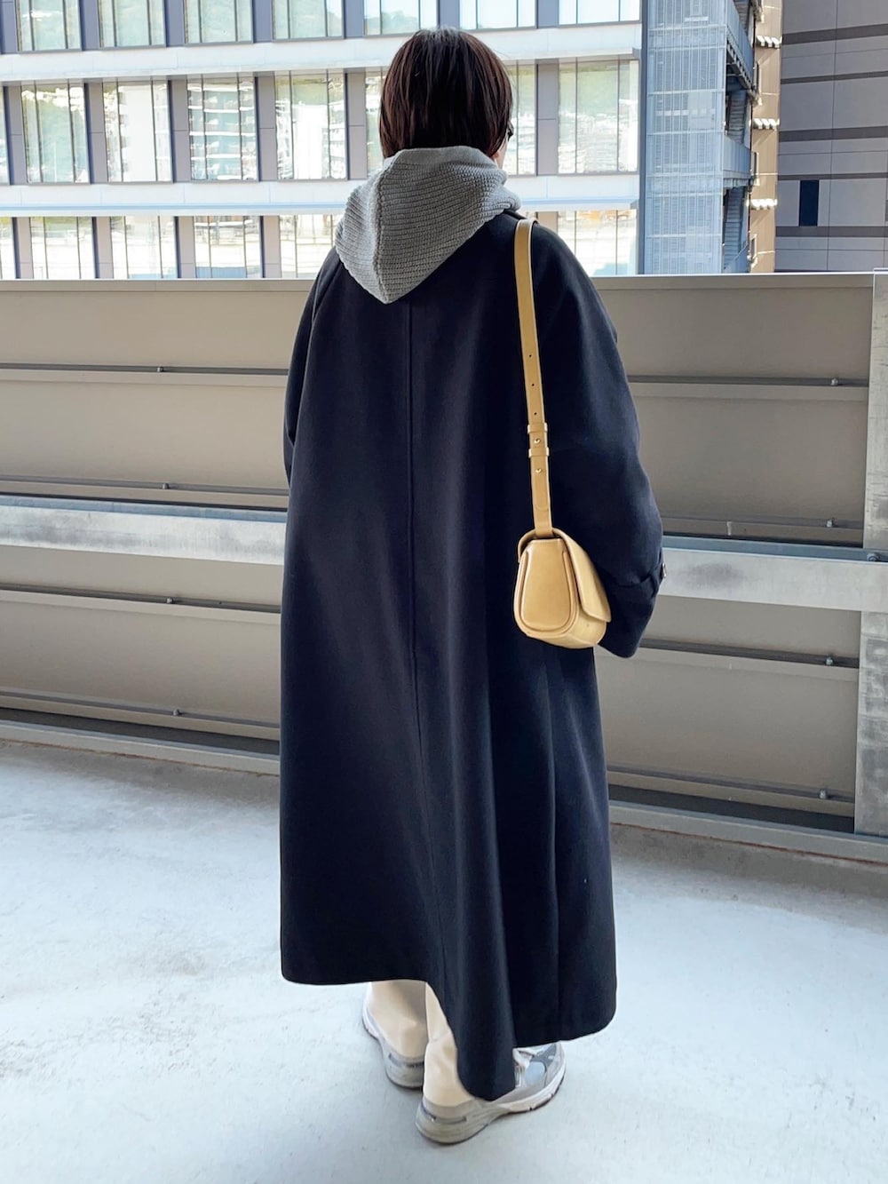 ブラック系のステンカラーコートを着用したレディースの秋コーディネートの2枚目の写真