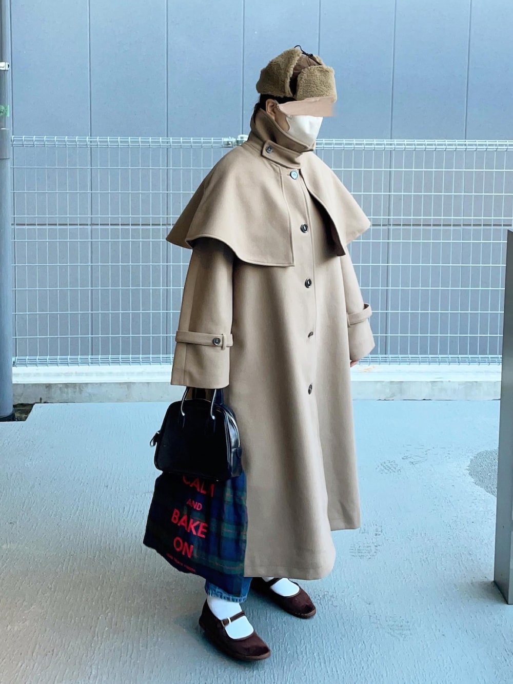 グリーン系のステンカラーコートを着用したレディースの冬コーディネートの3枚目の写真