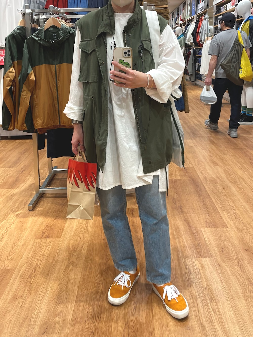 オレンジ系のスニーカー、グリーン系のベスト、ホワイト系のシャツ/ブラウスを着用したレディースの秋コーディネートの2枚目の写真