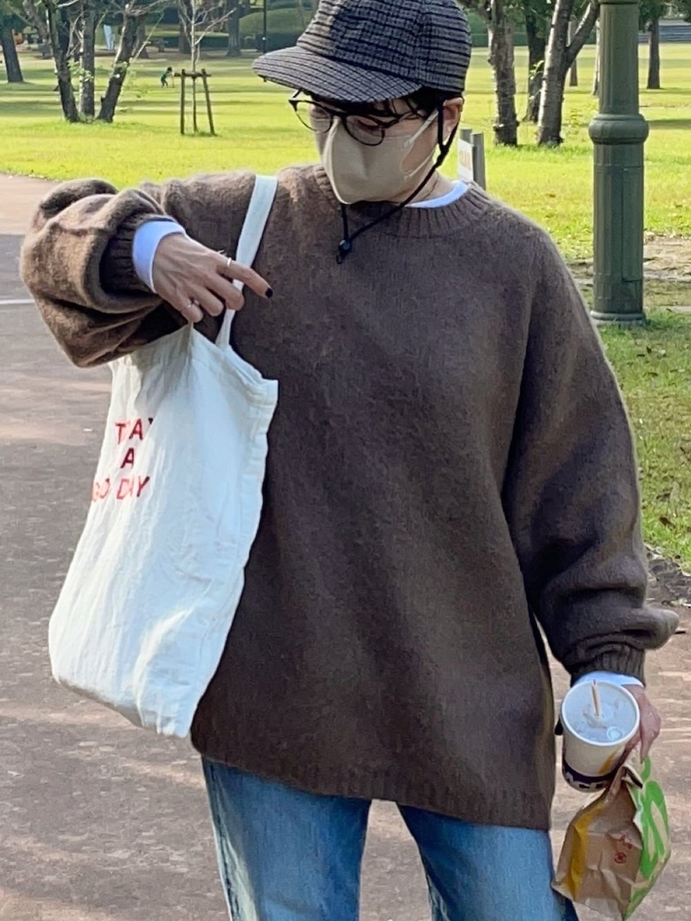 ブルー系のデニムパンツ、ホワイト系のスニーカー、ブラウン系のニット/セーターを着用したレディースの秋コーディネートの2枚目の写真