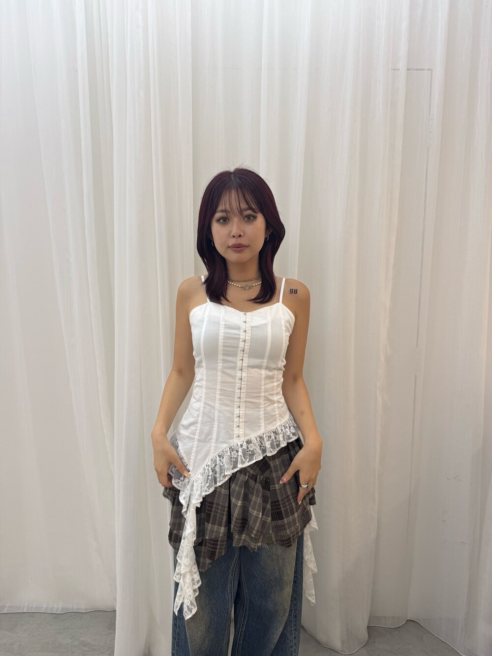 ホワイト系のキャミソール、ブラウン系のスカート、ブルー系のデニムパンツを着用したレディースの夏コーディネートの3枚目の写真