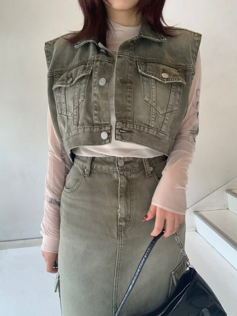 グリーン系のデニムジャケット、グリーン系のデニムスカート、ベージュ系のTシャツ/カットソーを着用したレディースの秋コーディネートの3枚目の写真