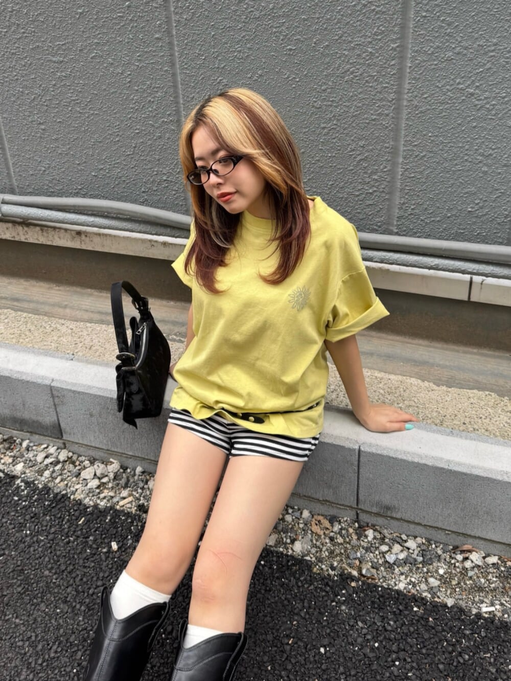 ブラック系のブーツ、ブラック系のハンドバッグ、イエロー系のTシャツ/カットソーを着用したレディースの夏コーディネートの4枚目の写真