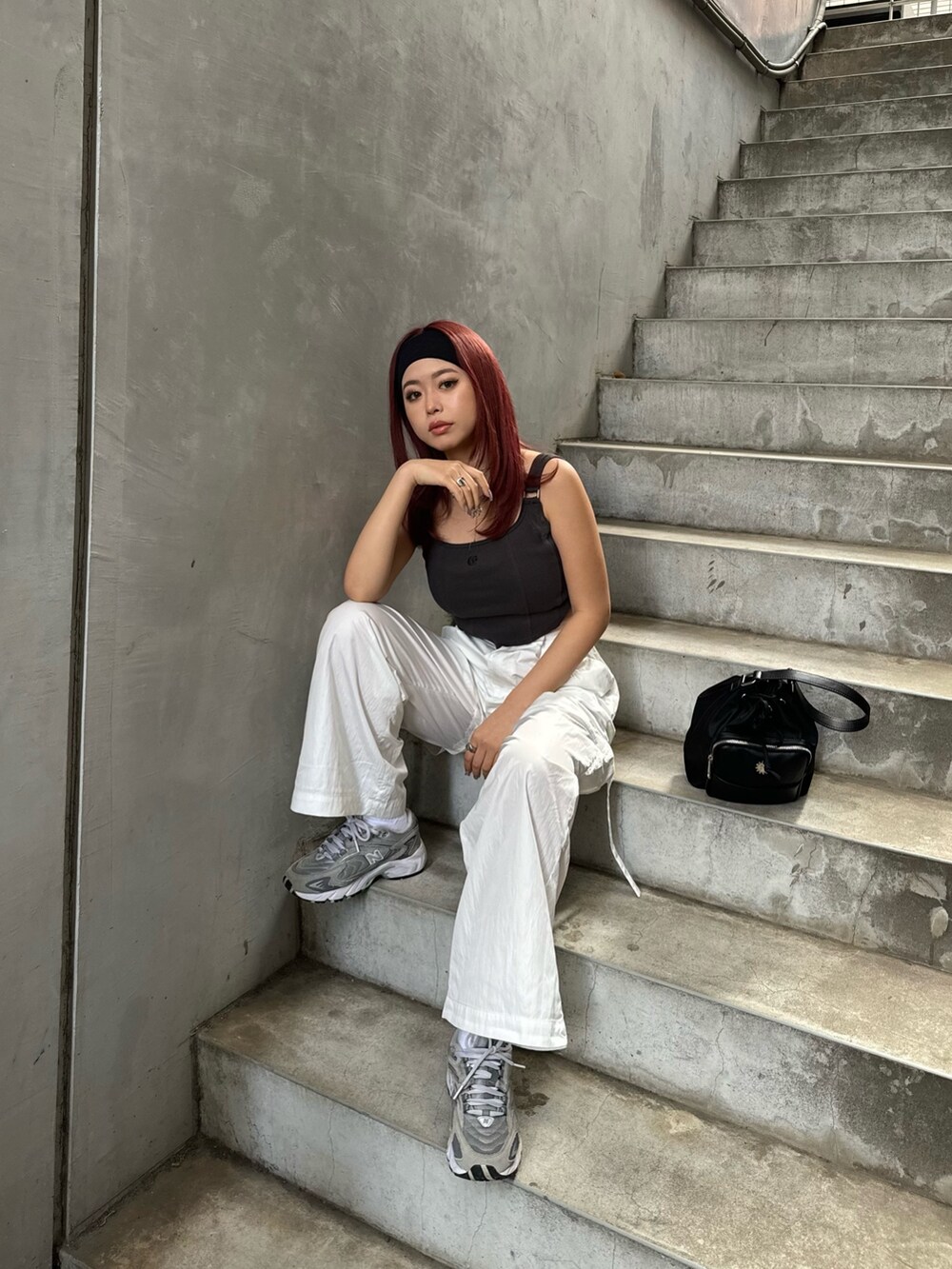 グレー系のキャミソール、ホワイト系のカーゴパンツ、ブラック系のショルダーバッグを着用したレディースの春コーディネートの2枚目の写真