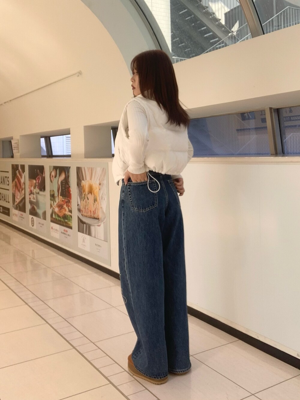 ホワイト系のダウンベスト、ホワイト系のニット/セーター、ブルー系のデニムパンツを着用したレディースの秋コーディネートの2枚目の写真