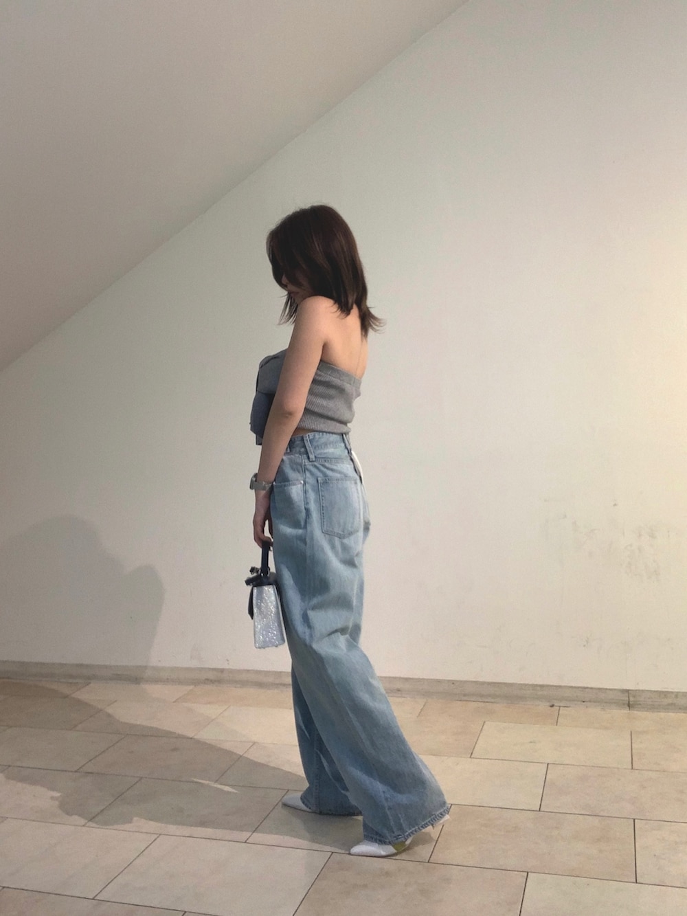 グレー系のチューブトップ、ブルー系のデニムパンツ、シルバー系のショルダーバッグを着用したレディースの春コーディネートの2枚目の写真