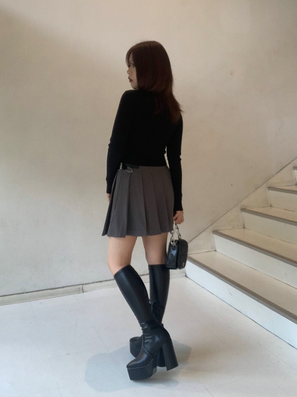 ブラック系のニット/セーター、グレー系のスカート、ブラック系のブーツを着用したレディースの秋コーディネートの3枚目の写真