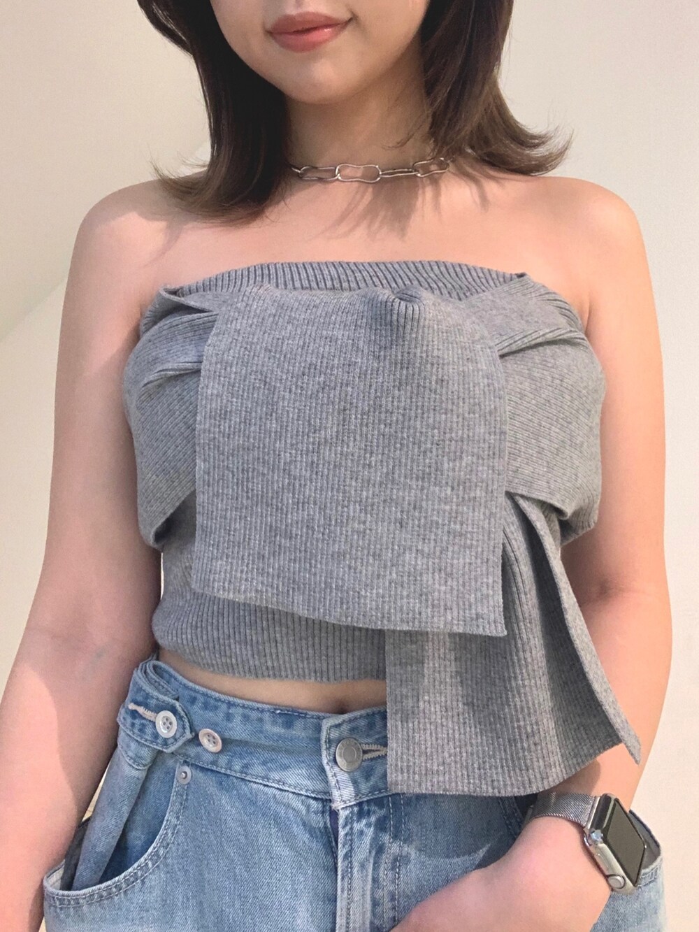 グレー系のチューブトップ、ブルー系のデニムパンツ、シルバー系のショルダーバッグを着用したレディースの春コーディネートの3枚目の写真