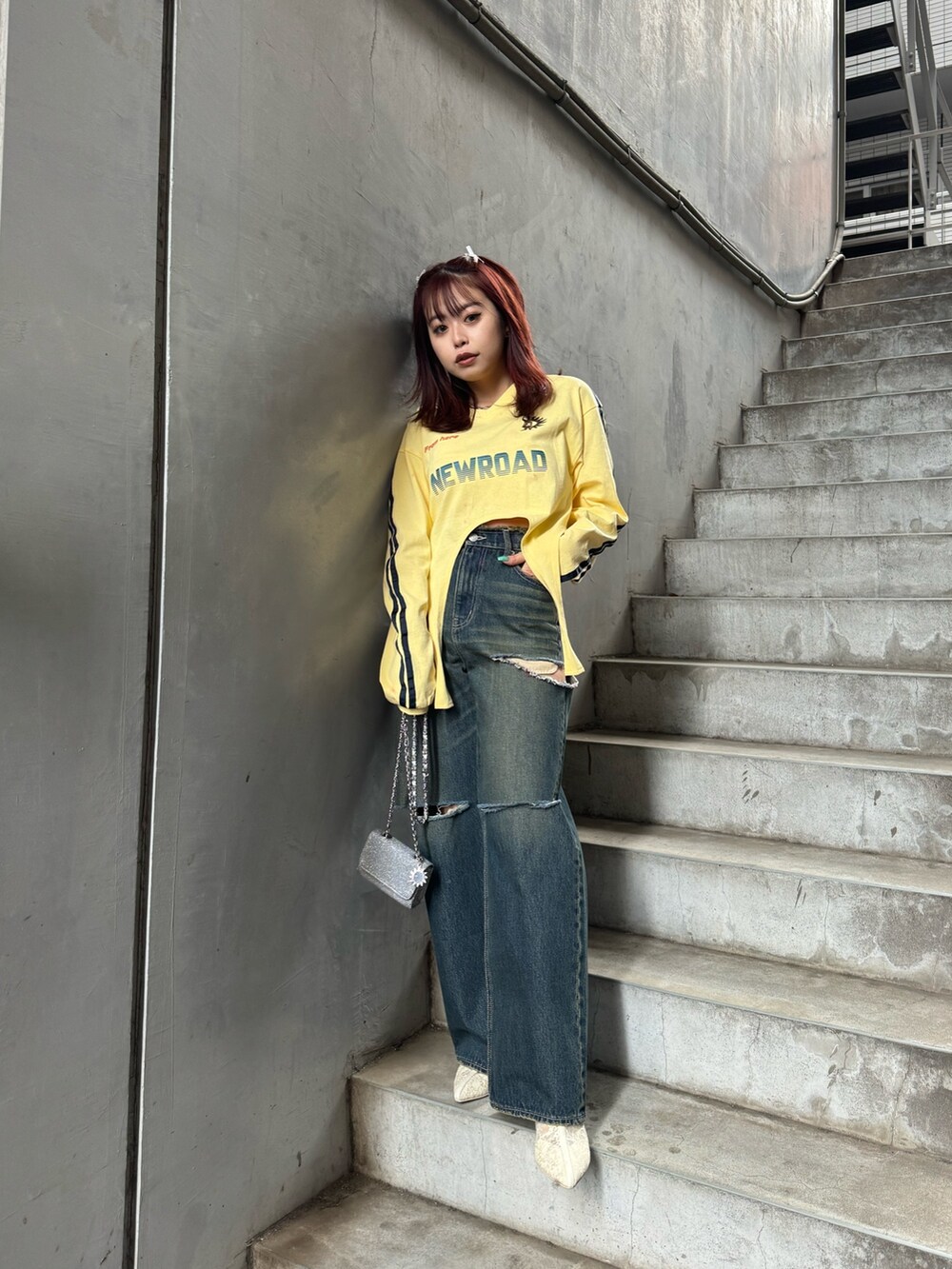 イエロー系のTシャツ/カットソー、ホワイト系のブーツ、シルバー系のショルダーバッグを着用したレディースの冬コーディネートの4枚目の写真