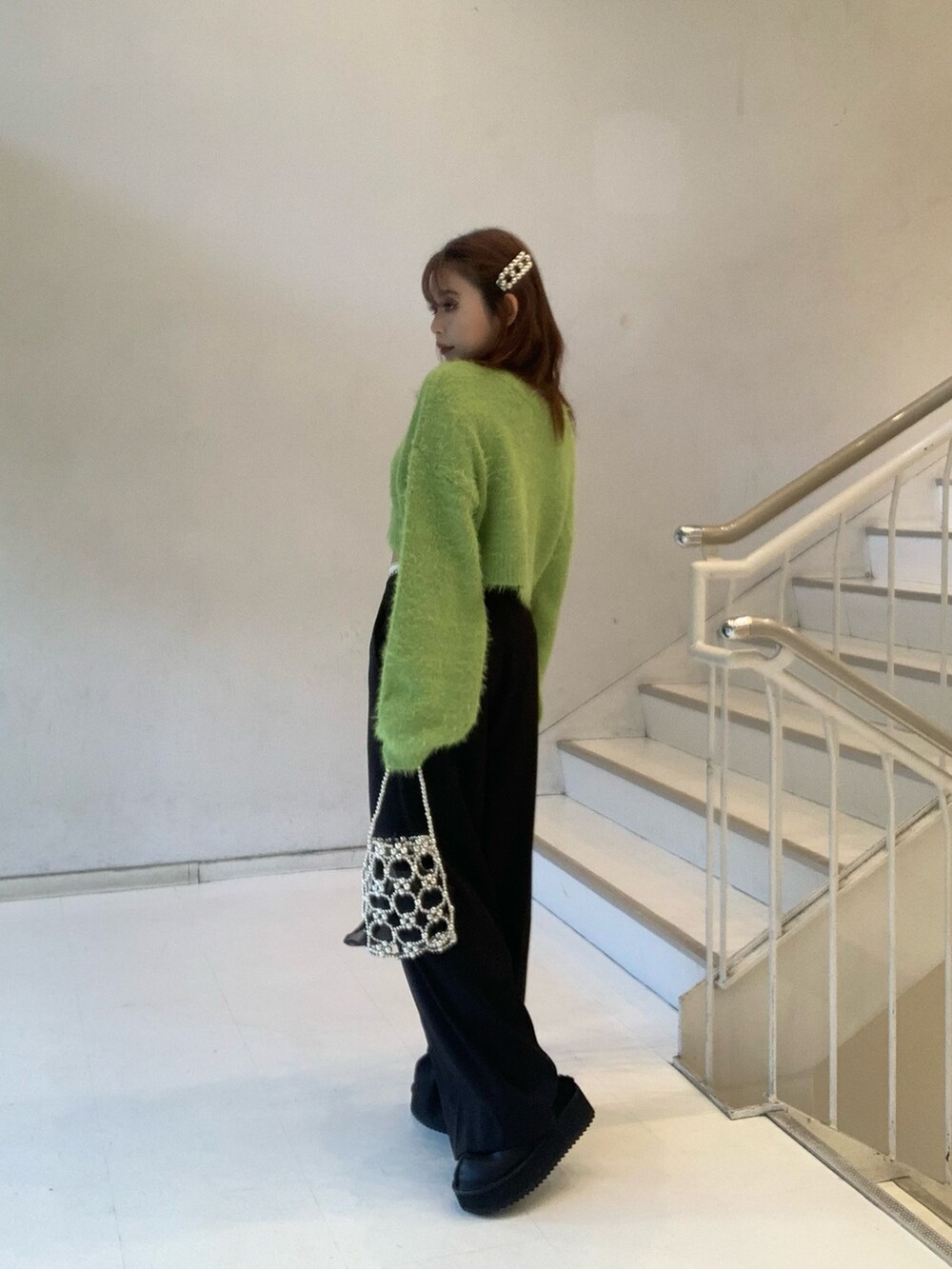 グリーン系のニット/セーター、ブラック系のその他パンツ、ブラック系のスリッポンを着用したレディースの冬コーディネートの2枚目の写真
